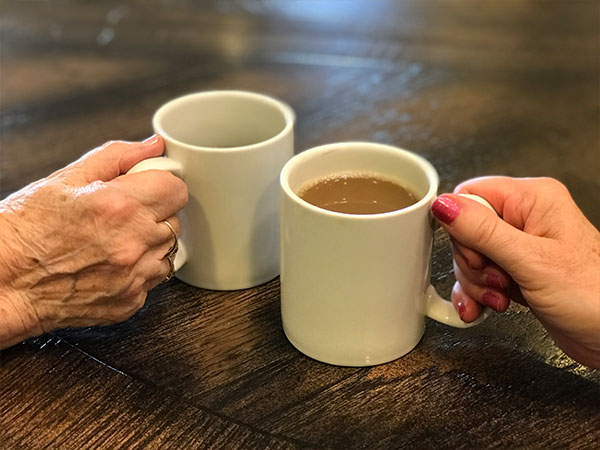 Senior woman enjoying coffee with careworker